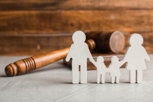 Silhouette of parents holding hands with two children next to a gavel to symbolize grooming, including its definition, legal implications, and seeking help for it.