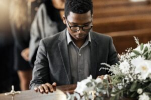 black man grieving at a coffin in sterling heights